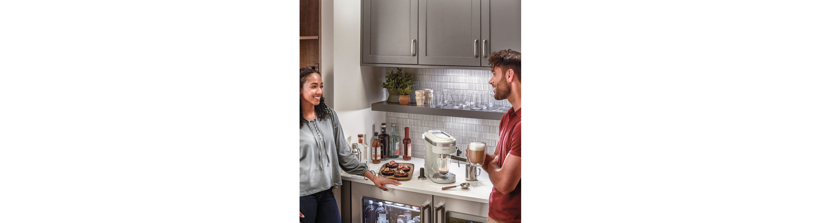 Couple chatting next to bar with espresso maker and undercounter refrigeration