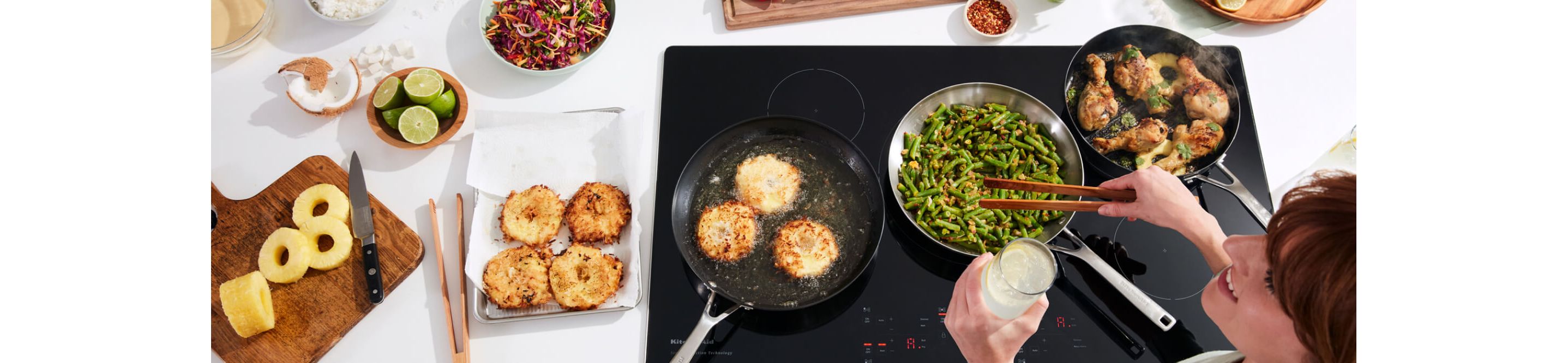A person preparing various types of food on a KitchenAid® Cooktop