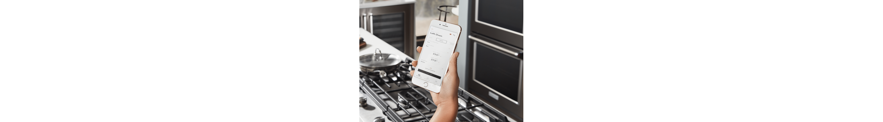 Hand holding a smartphone connected to a KitchenAid® smart oven