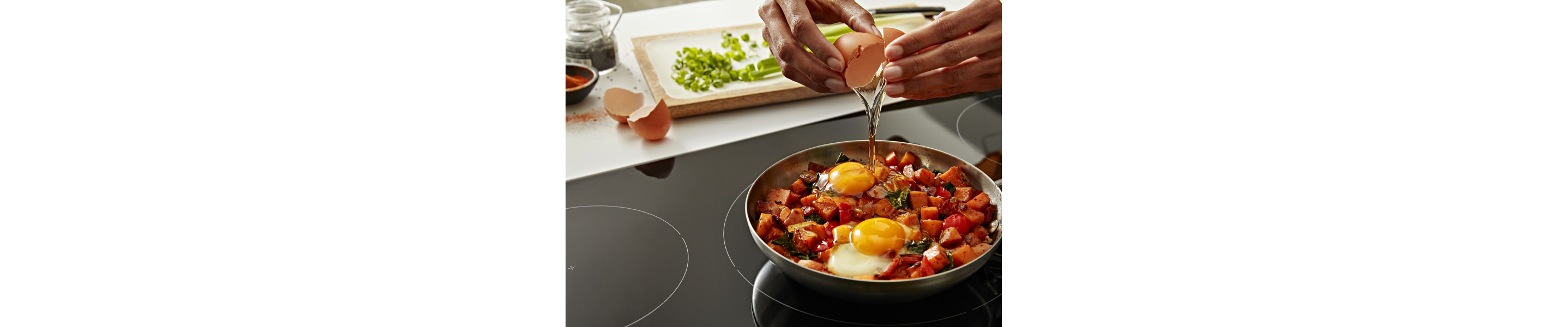 Hands cracking an egg over a pan