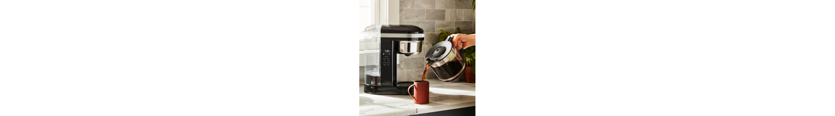 Black KitchenAid® drip coffee maker pouring coffee into a mug