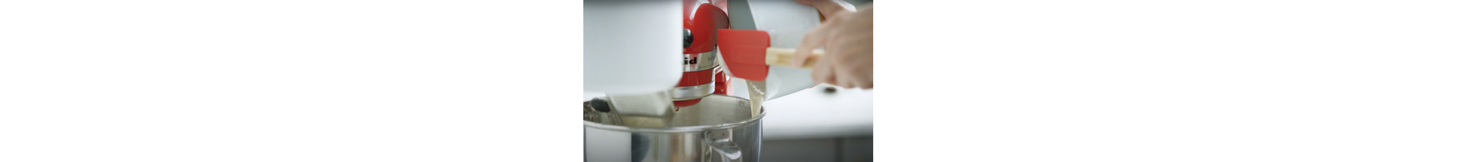 A person adding sourdough starter to a KitchenAid® stand mixer bowl.