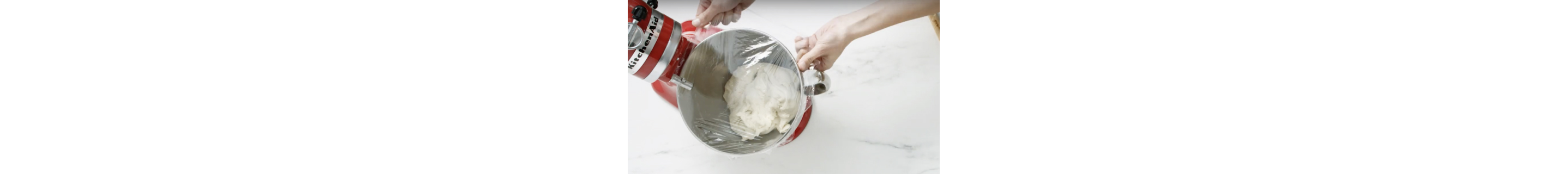A stand mixer bowl being covered with cling film.
