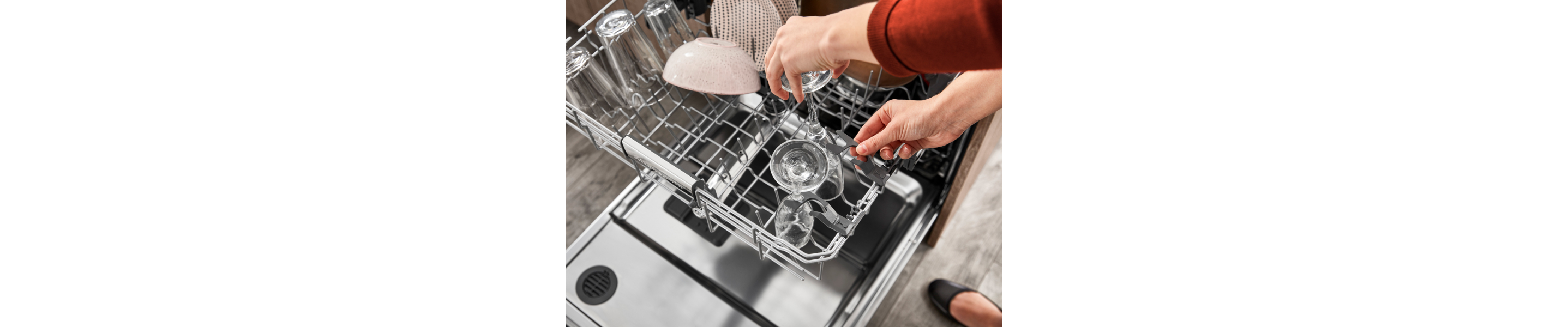 Person loading glassware into the top rack of a dishwasher