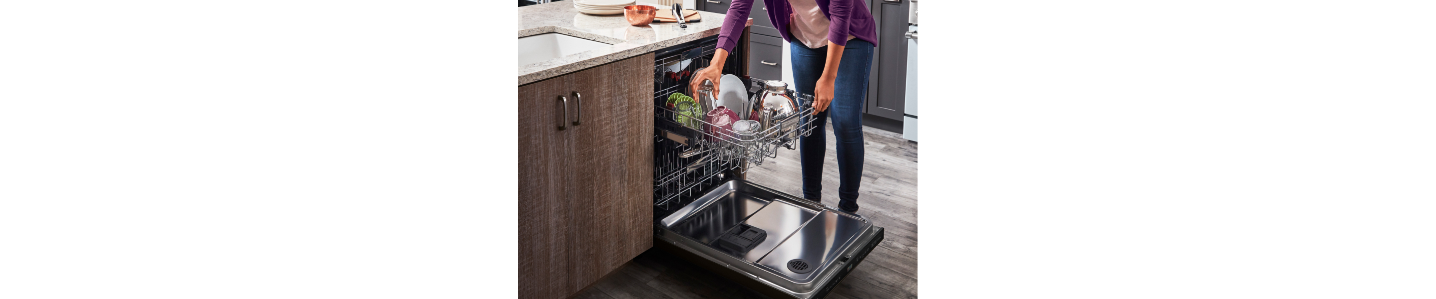 Woman loading dishes into a three rack dishwasher