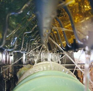 Water spraying inside a dishwasher with dishes