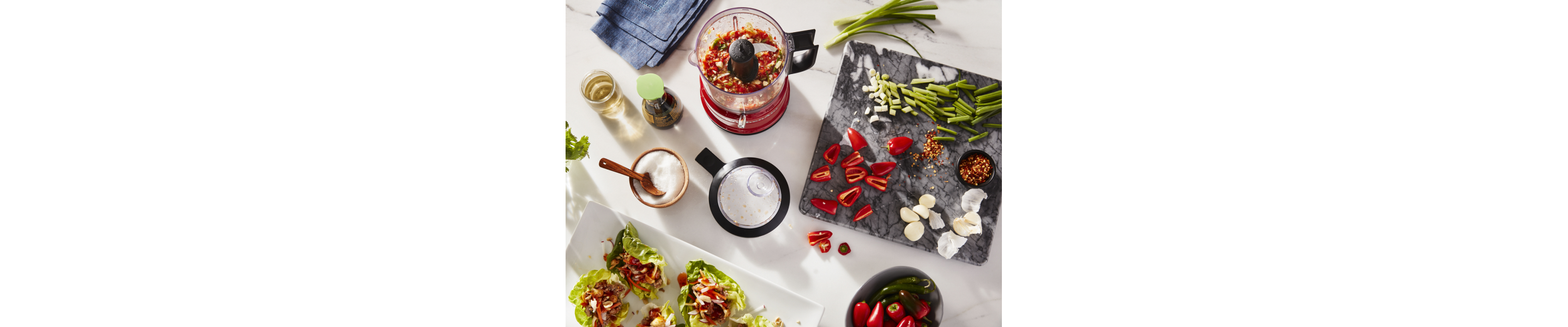 Vegetables and herbs on a cutting board and in a food processor