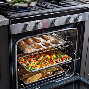 Open range oven with three trays of food inside