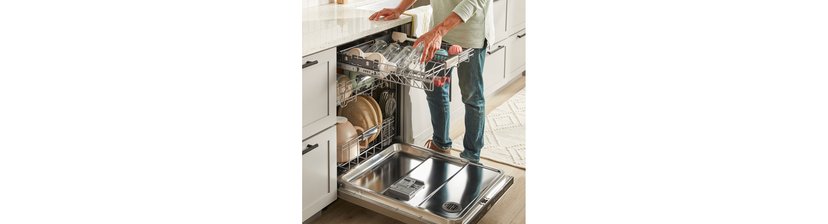 Man loading glasses in third rack of dishwasher