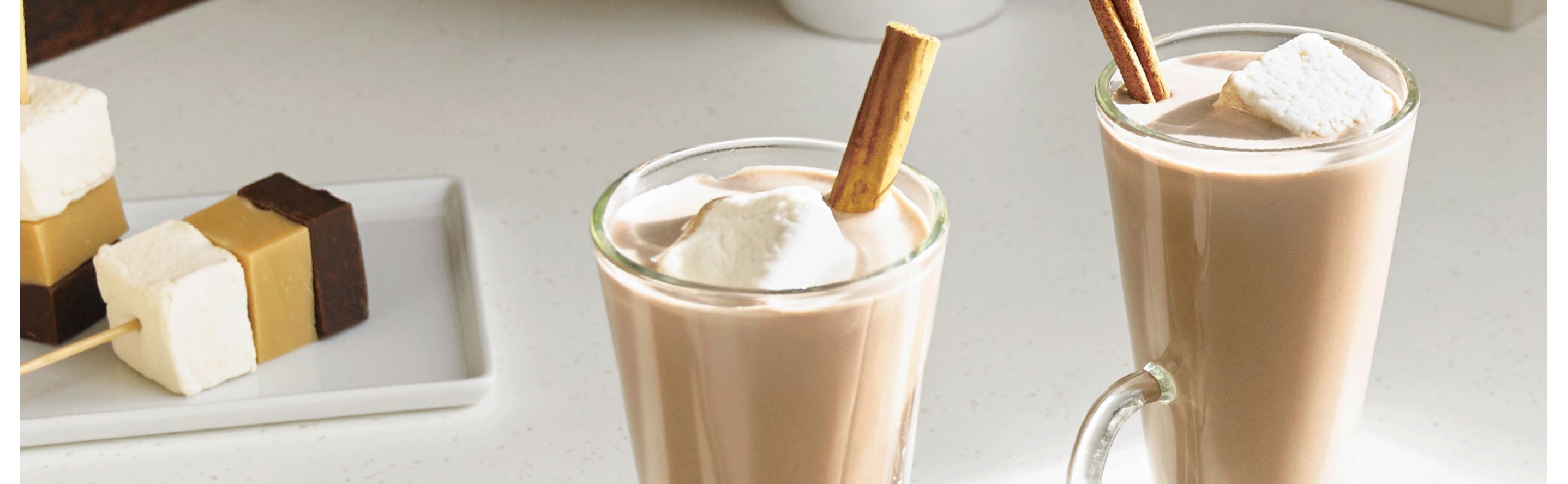 Coffee beverage in glass mugs garnished with marshmallows and cinnamon
