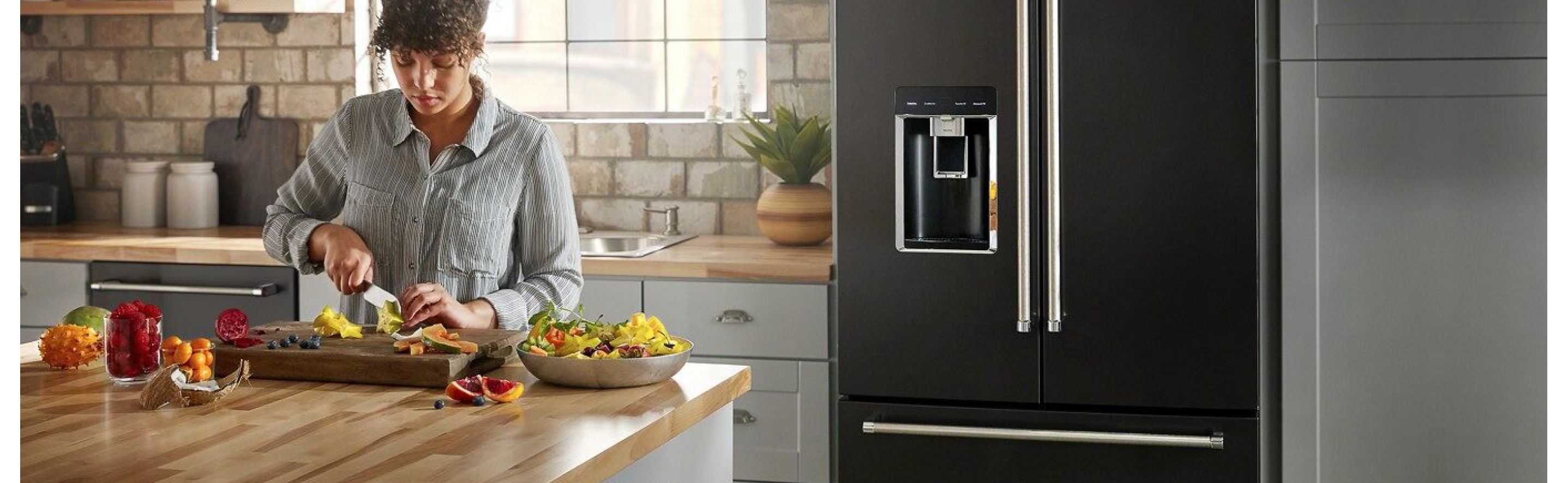 Woman chopping fruit in front of a French door refrigerator