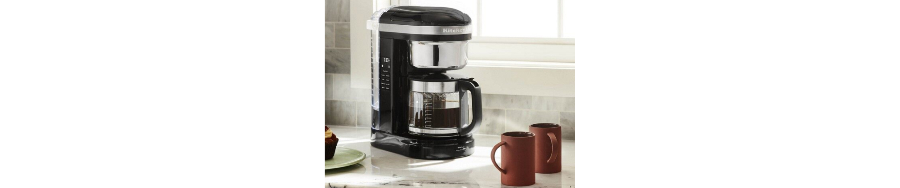 KitchenAid® 12 Cup Drip Coffee Maker full of coffee on counter with mugs