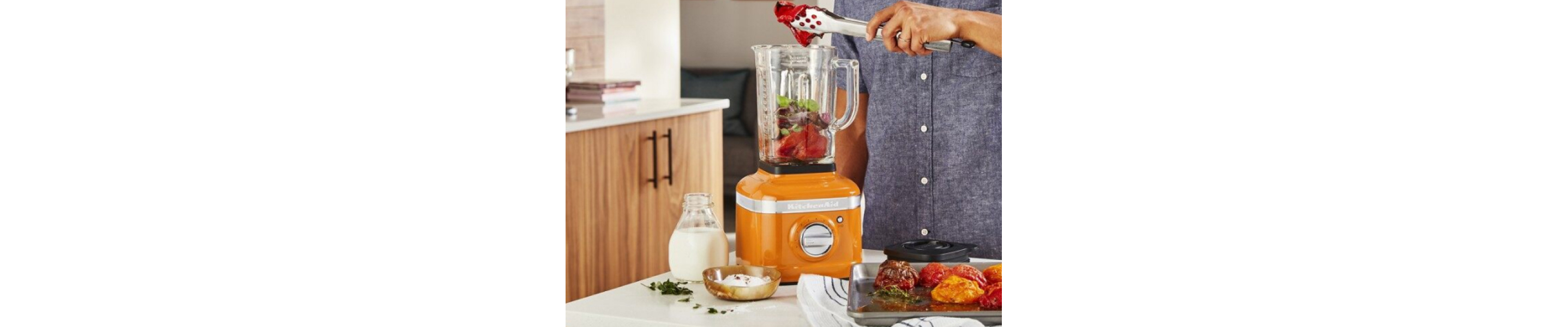 Person adding ingredients to orange KitchenAid® countertop blender