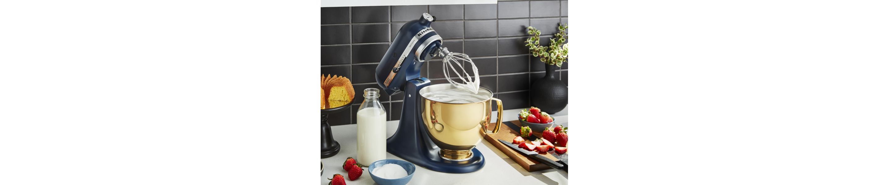 Blue KitchenAid® stand mixer with gold mixing bowl and wire whisk attachment