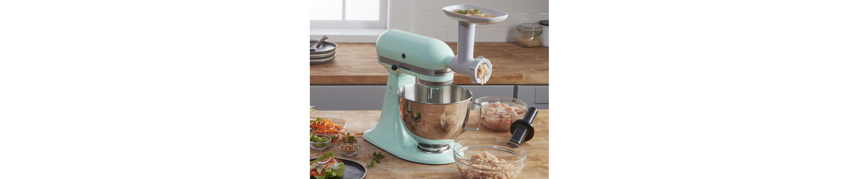 Mint green KitchenAid® stand mixer with the Food Grinder Attachment grinding chicken