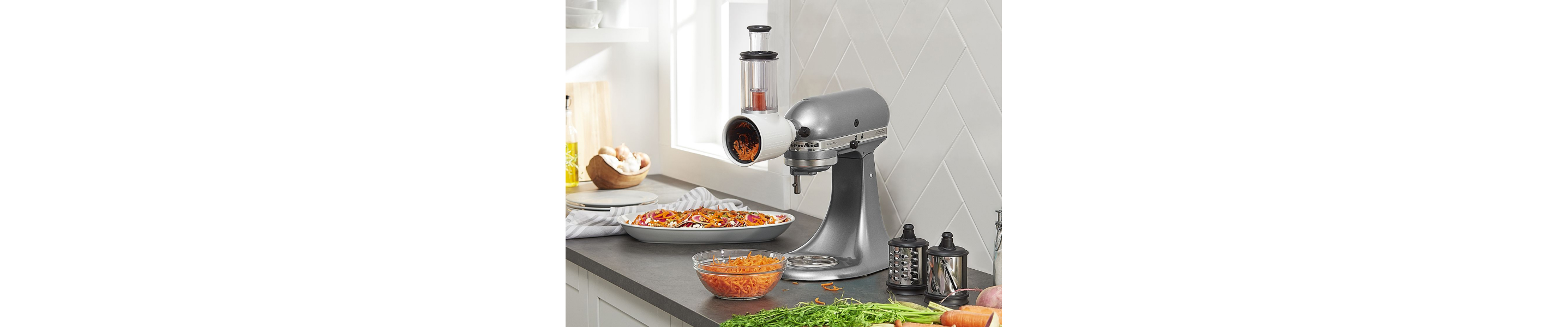 Silver KitchenAid® stand mixer with the Fresh Prep Slicer/Shredder Attachment shredding carrots