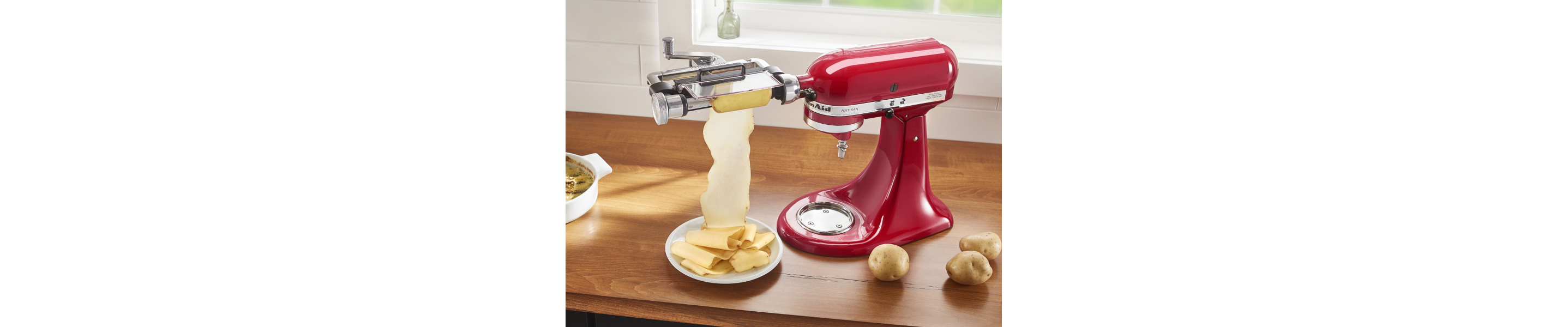 Red KitchenAid® stand mixer with the Vegetables Sheet Cutter Attachment cutting potatoes