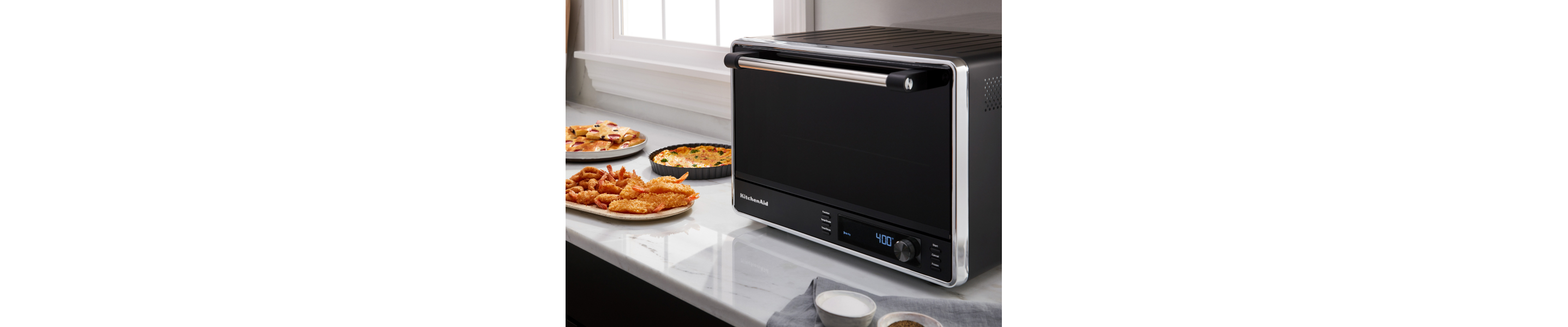 Black and silver KitchenAid® countertop oven on counter with food