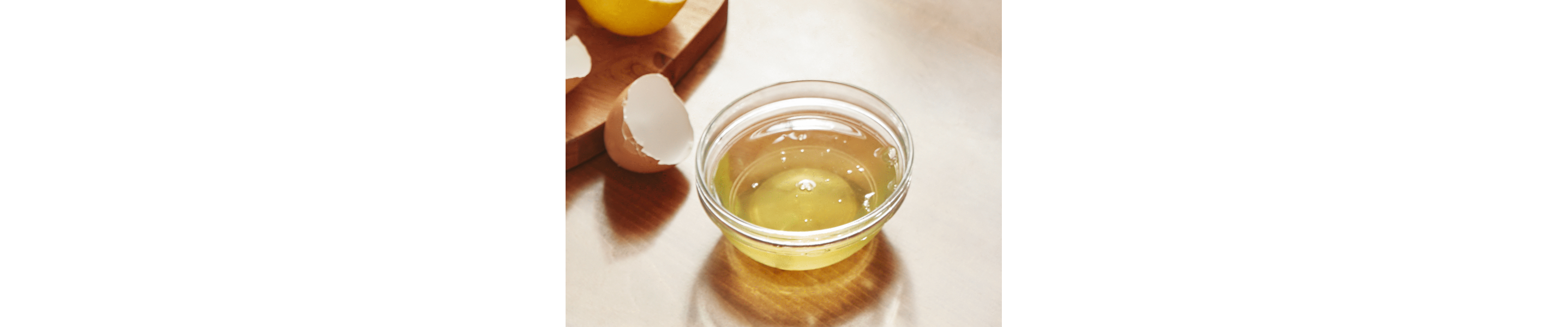 A cup of oil next to cracked eggs