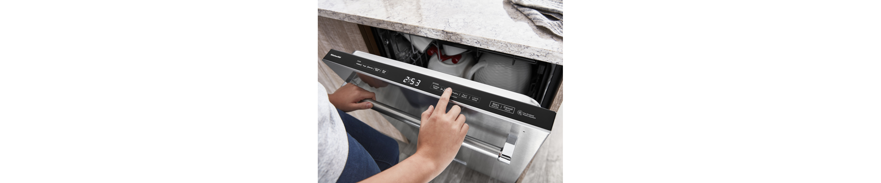 A closeup of a person using the control pad of a KitchenAid® dishwasher.