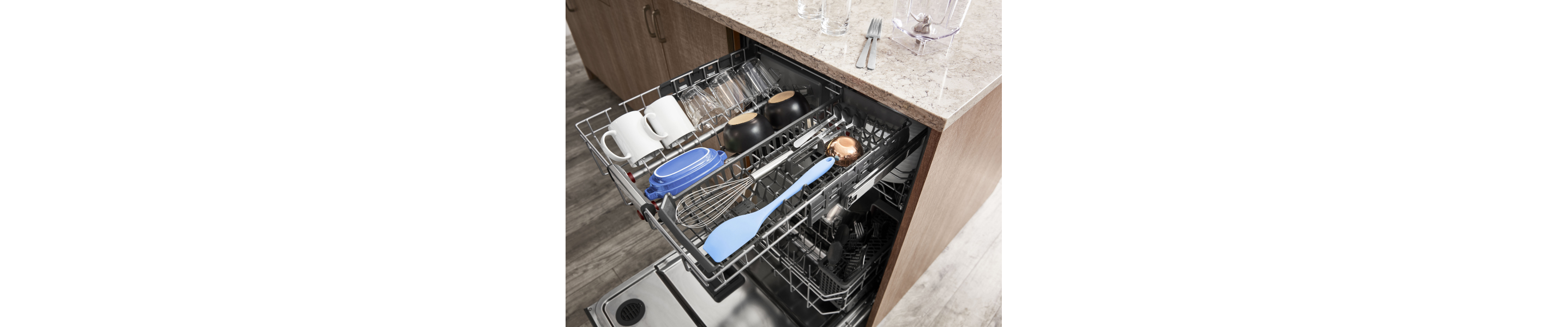 The top rack of a KitchenAid® dishwasher with utensils and glassware.