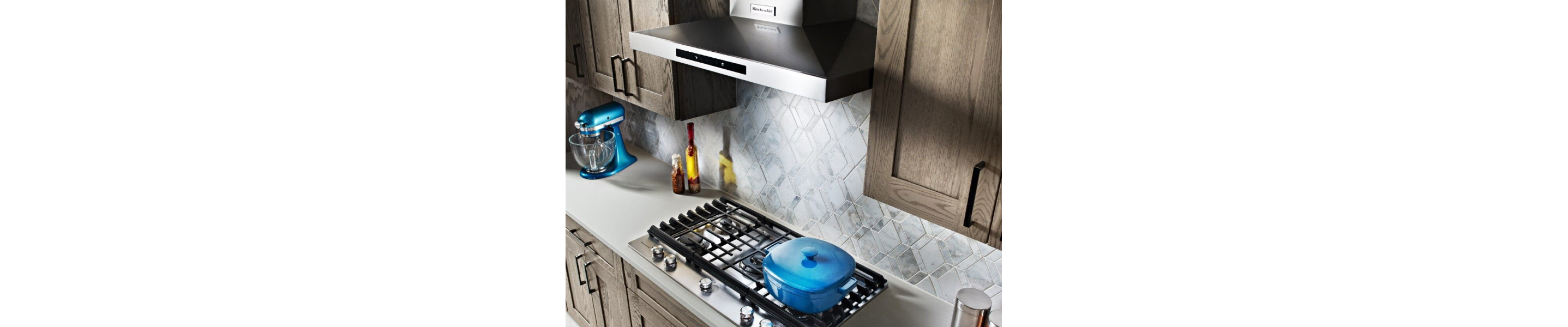 KitchenAid® wall mount range hood above gas stovetop with a blue pot