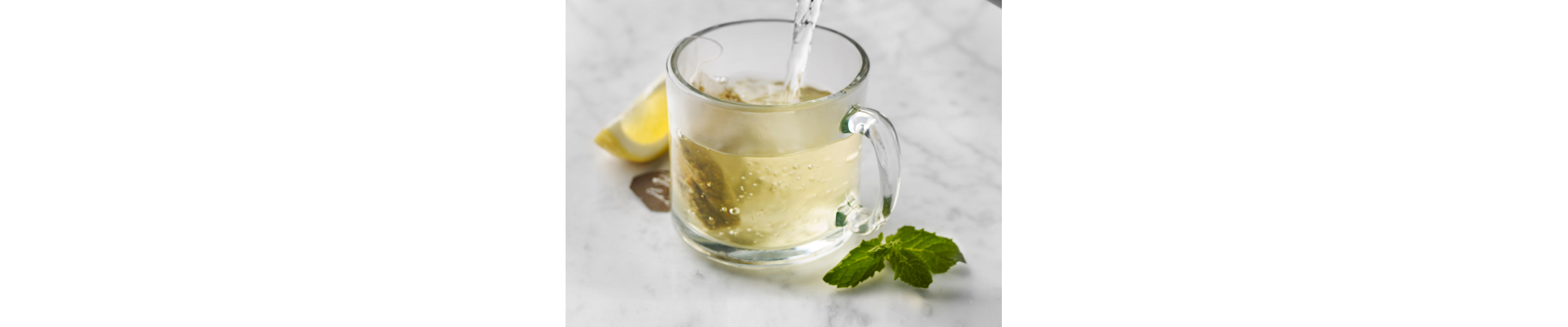 Glass mug of green tea with mint and lemon