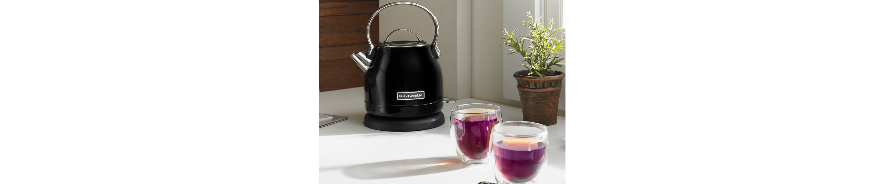 Black KitchenAid® electric kettle next to two glasses of purple tea