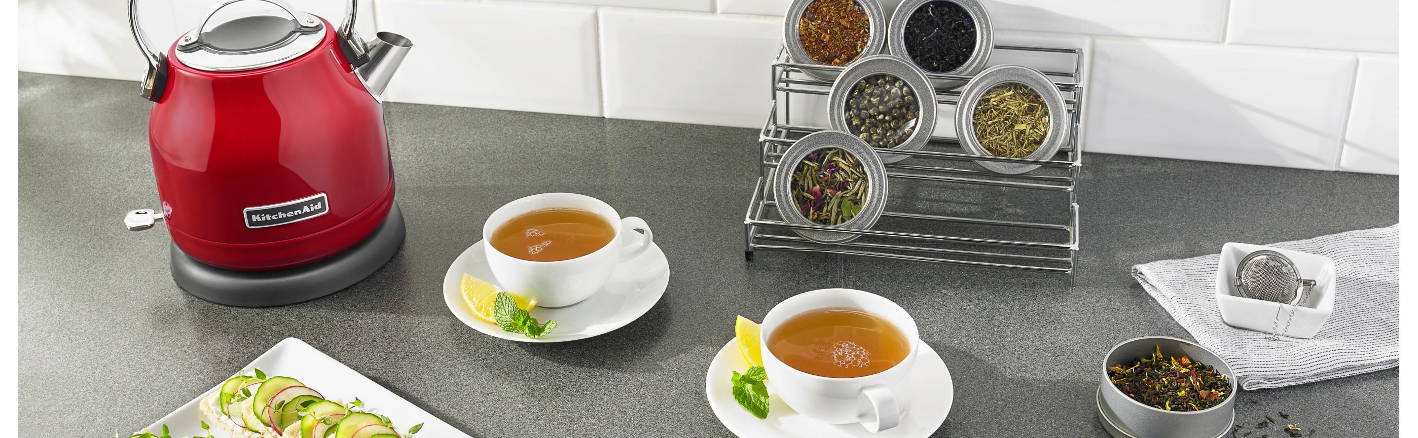 Red KitchenAid® electric kettle next to two cups of tea