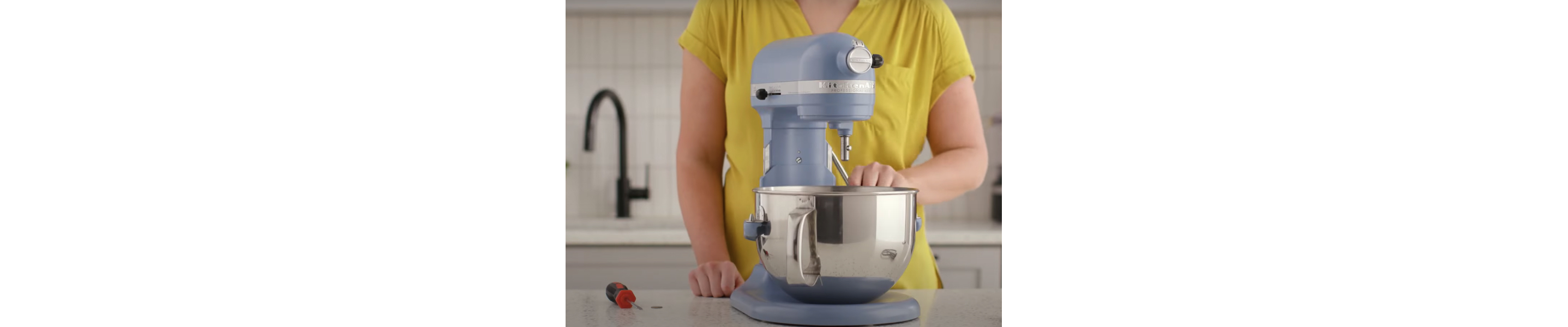 A person lowering the bowl of a blue bowl-lift stand mixer