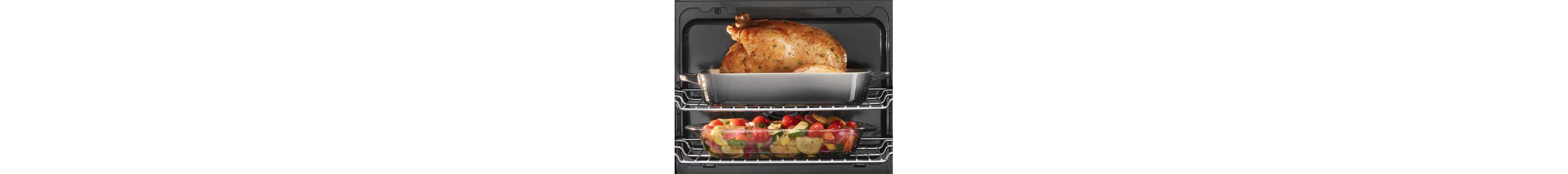 Two oven racks holding a turkey in a dish and a casserole of vegetables 