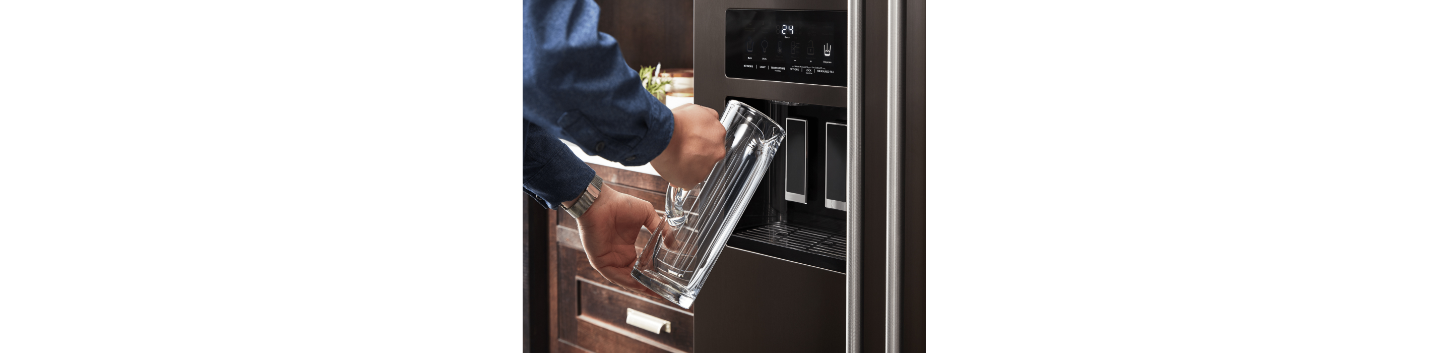 Man filling a tall glass mug with water from a fridge water dispenser 