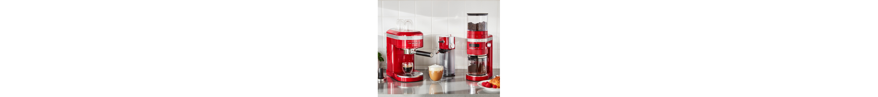 A KitchenAid® espresso machine and burr coffee grinder in a modern kitchen with an espresso, frothy cappuccino and pastry