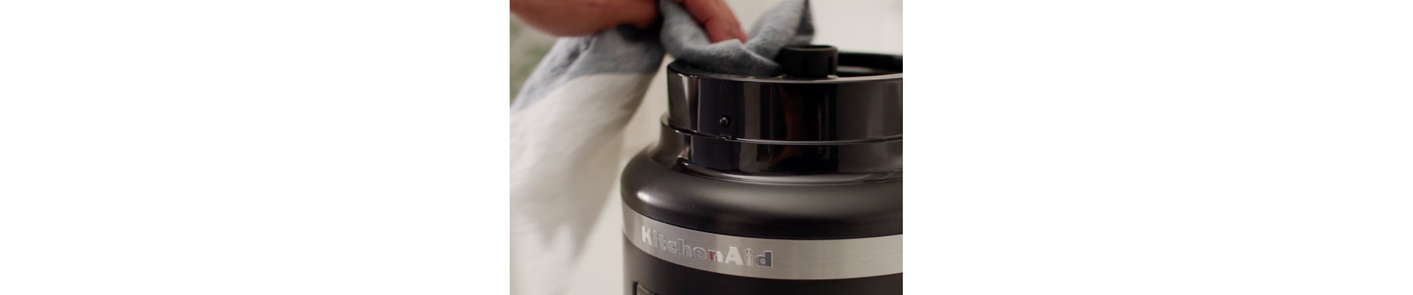 A person cleaning the base of a disassembled food processor