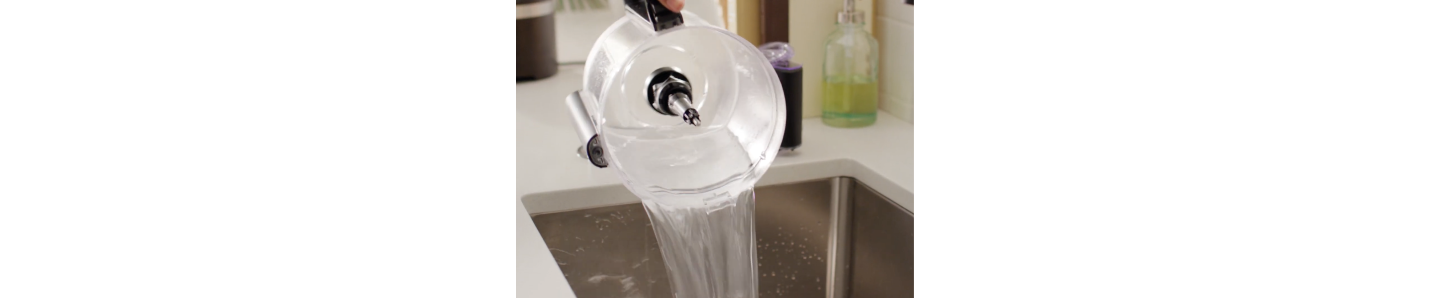 A person cleaning the bowl of a disassembled food processor