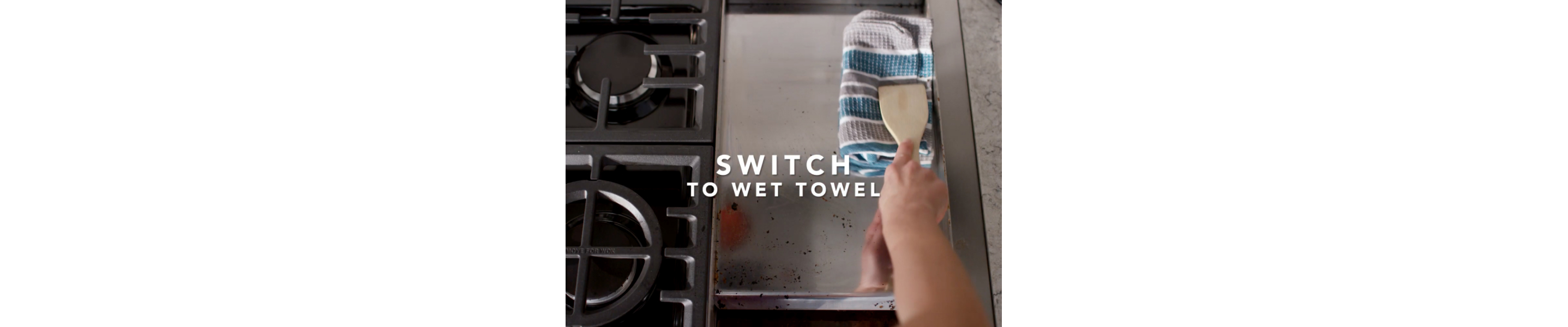 Wiping griddle clean with towel and wooden spoon 