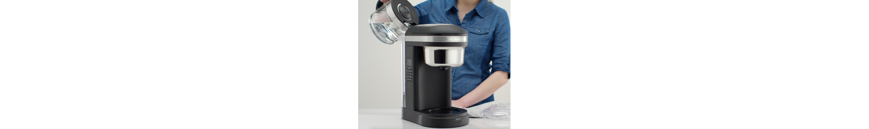 Woman pouring water into coffee machine to rinse after descaling