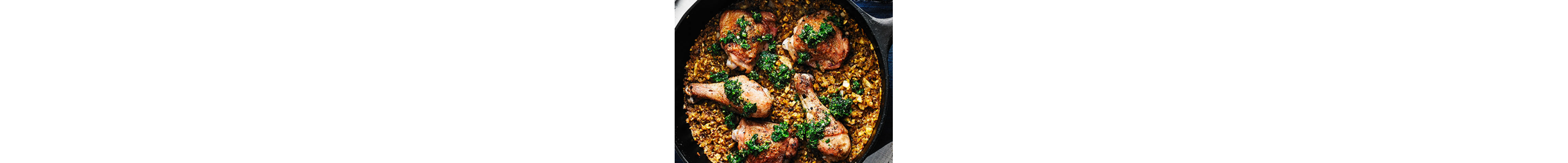 A cooking pan with chicken legs and seasoned rice.