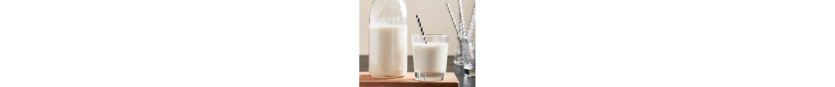 A closeup of a glass milk container next to a glass of milk.
