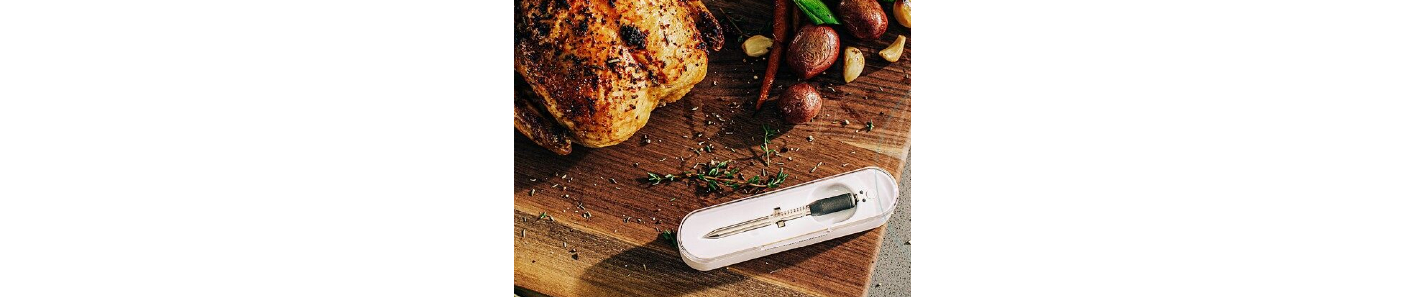 Rotisserie chicken on a cutting board next to a food thermometer and roasted potatoes