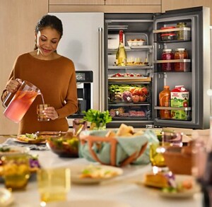 A woman pours a drink while standing in front of her open refrigerator