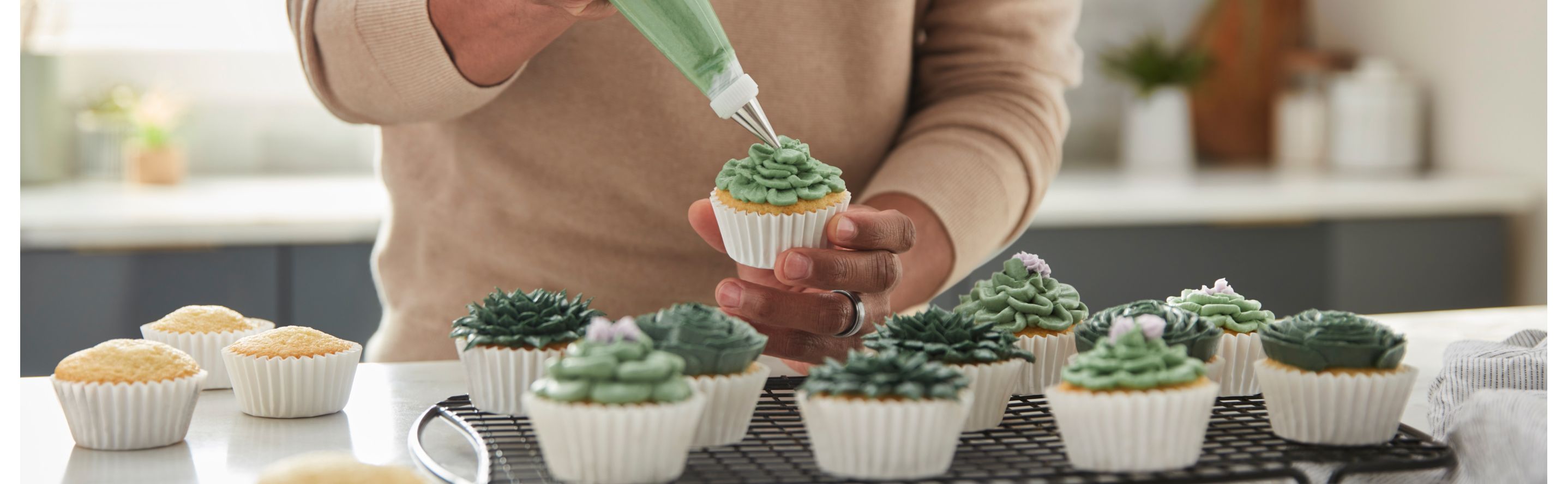 Person piping frosting onto a cupcake
