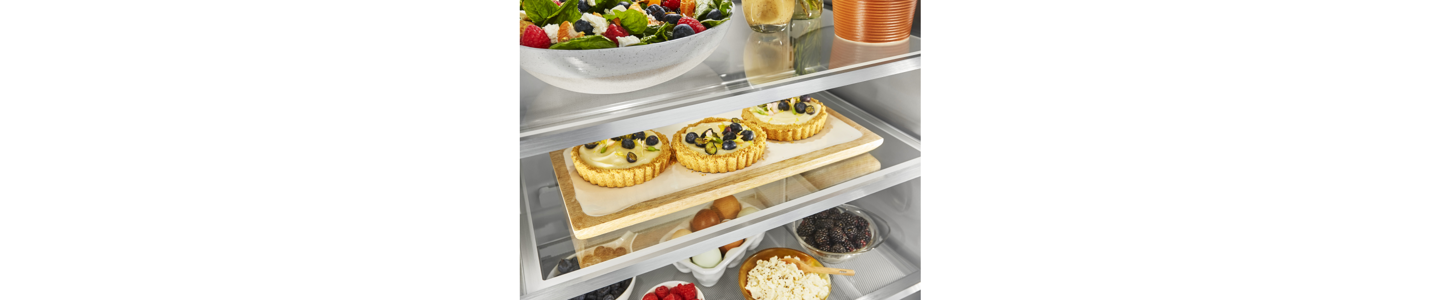 Three custard tarts topped with fruit inside a KitchenAid® refrigerator