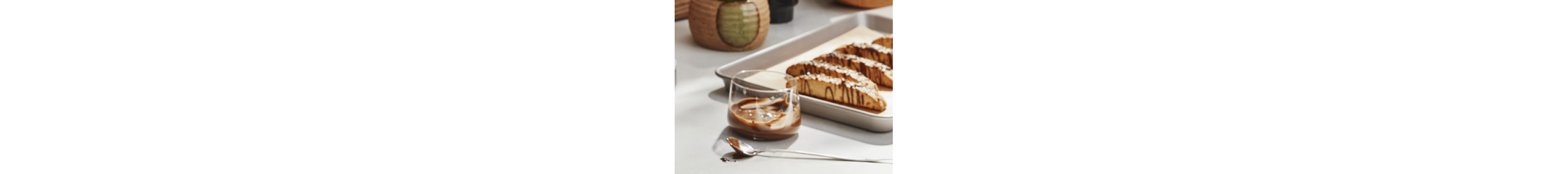 Mocha syrup in a glass cup beside homemade biscotti