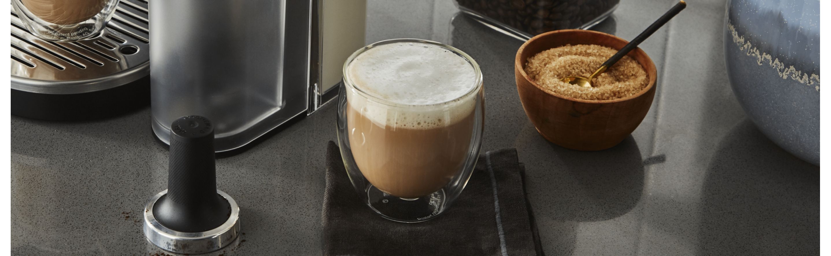 Espresso drink next to bowl of sugar