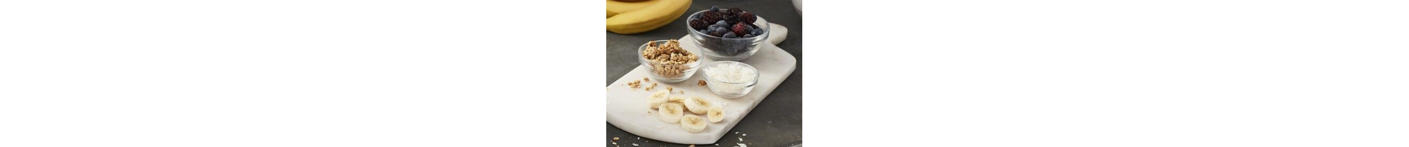 Berries, bananas and other mix-ins sitting on cutting board