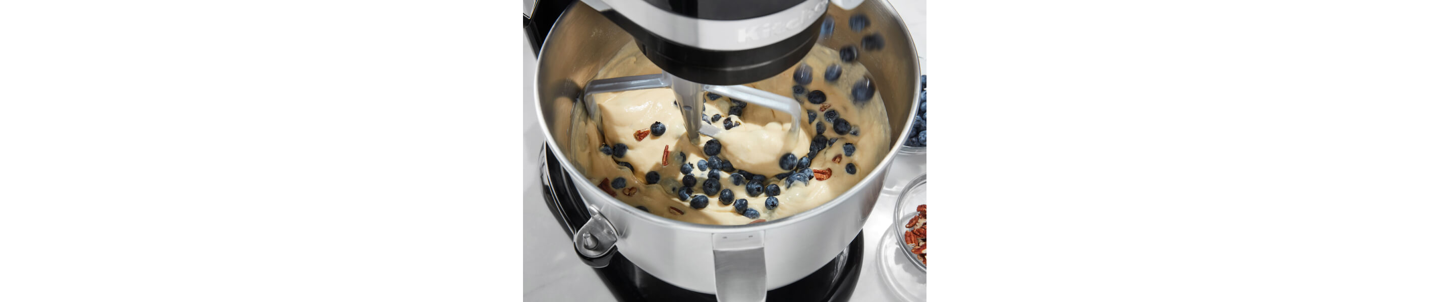  Birds-eye view of black KitchenAid® stand mixer mixing blueberries into batter