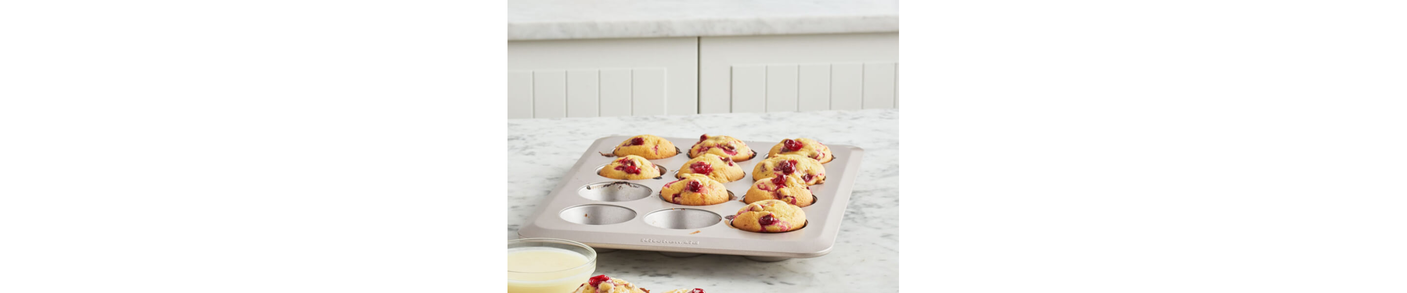 Partially empty muffin tin filled with baked cranberry muffins
