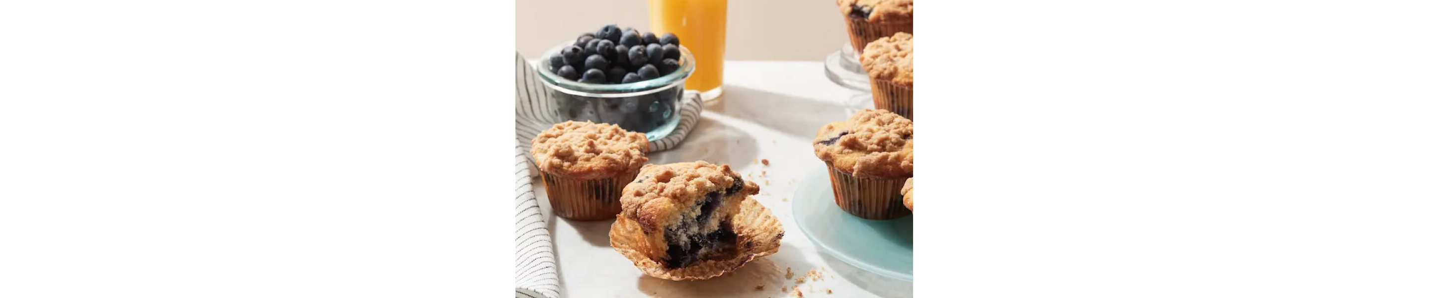 Partially eaten blueberry muffin topped with streusel inside of a muffin liner