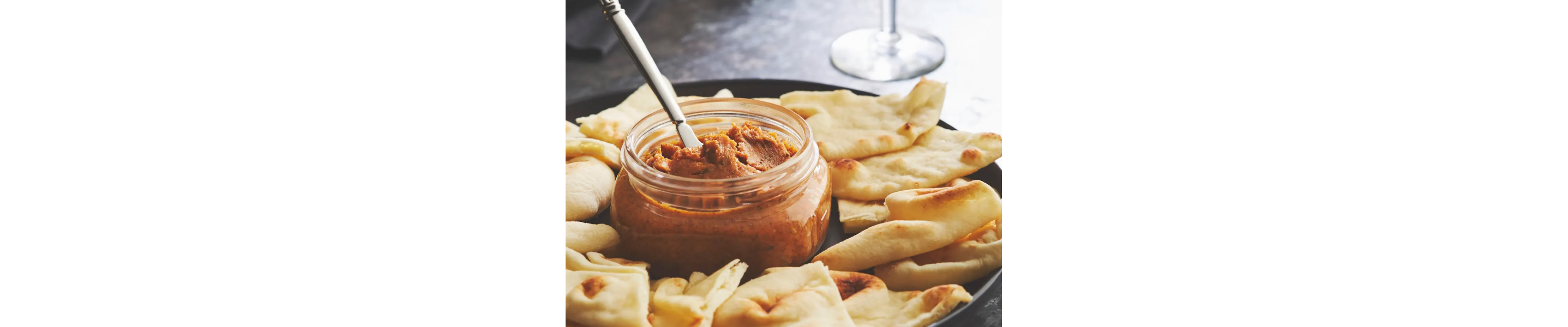 Jar of butter with pita triangles around it
